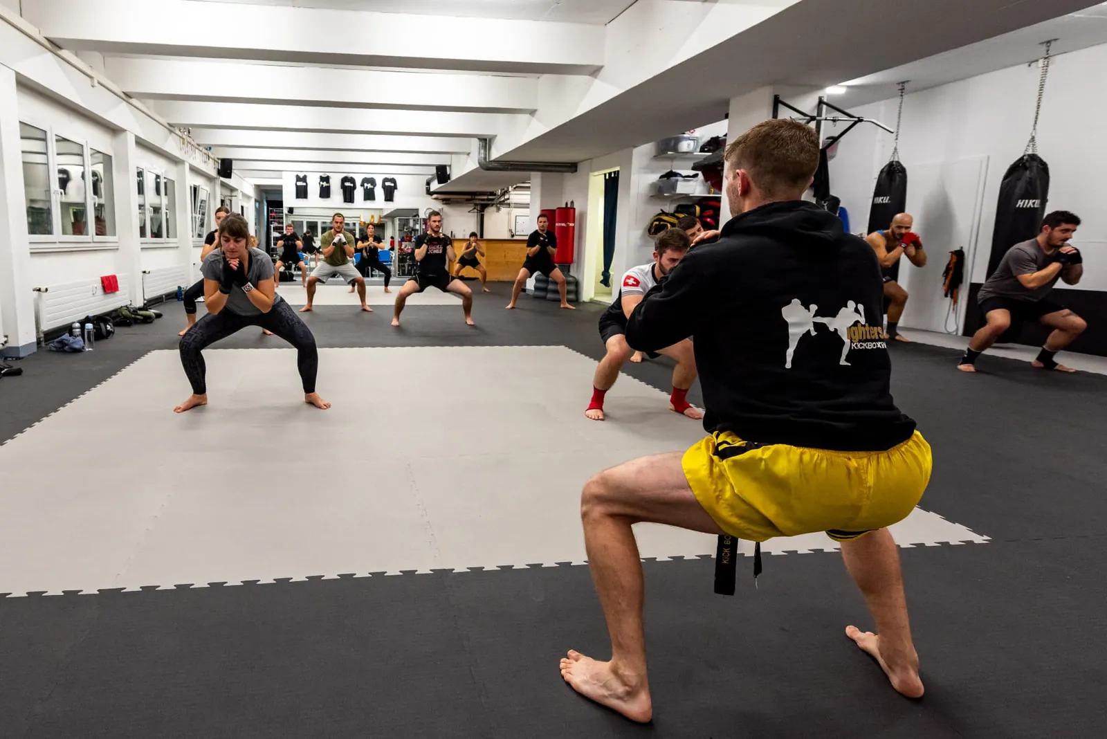 Gruppe macht Kniebeugen unter Anleitung des Trainers