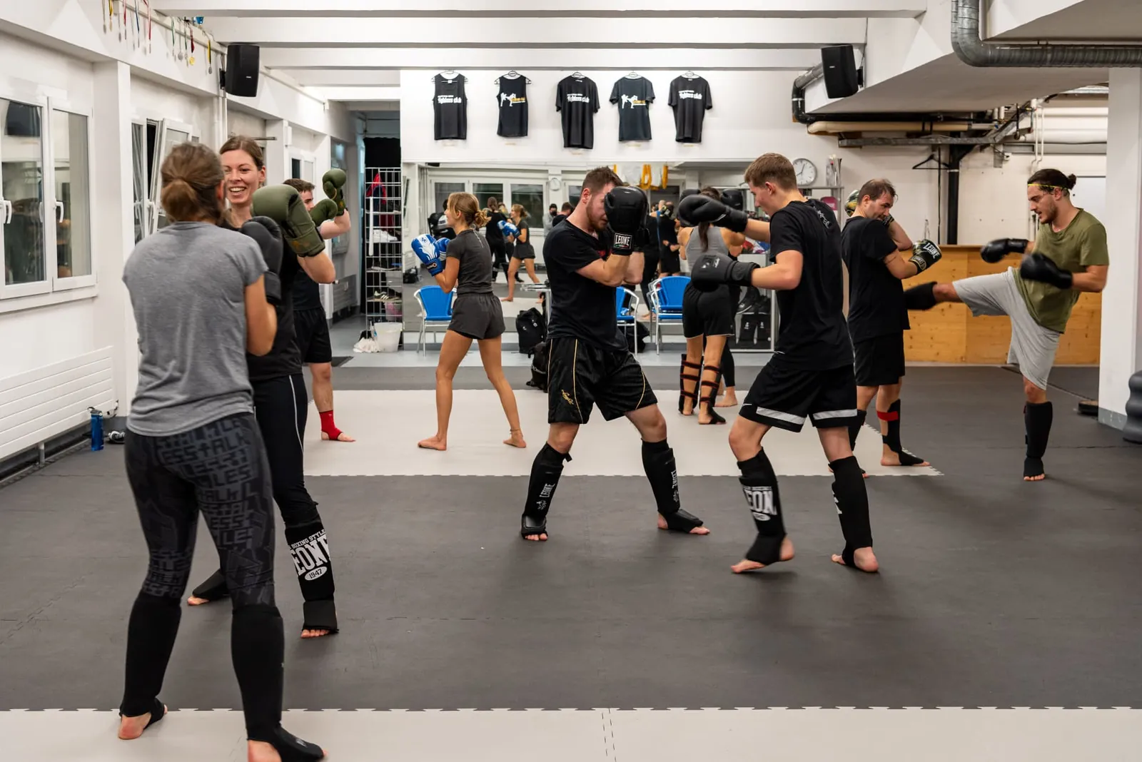 Paare üben Schlag- und Tritttechniken im Kickboxtraining in Bern